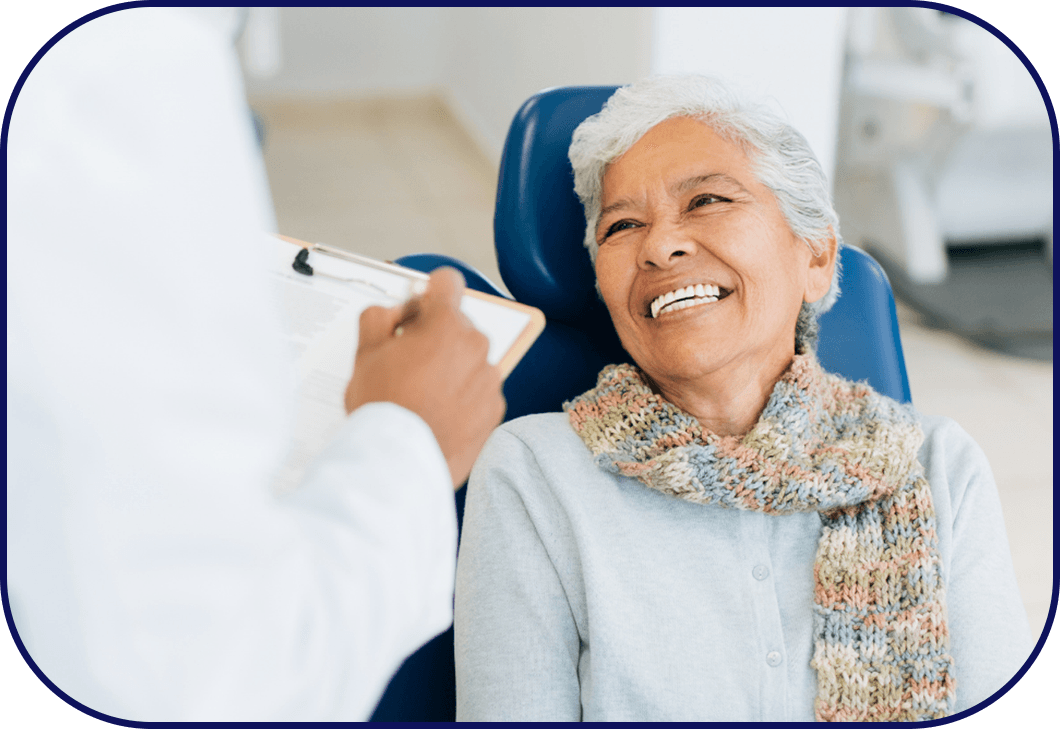 Elderly woman smiles broadly while listening to her dental hygienist