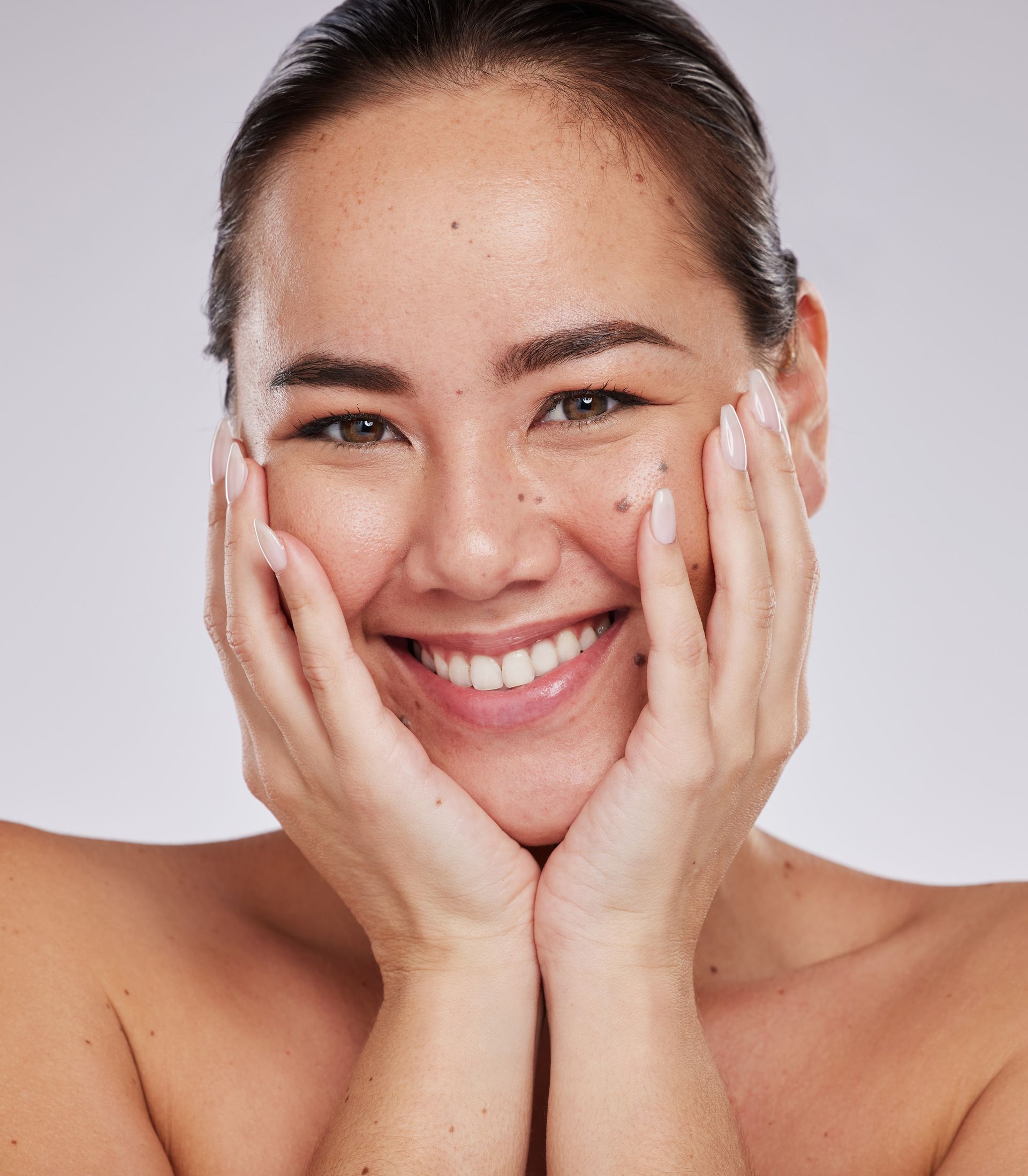 a woman is smiling with her hands on her face .
