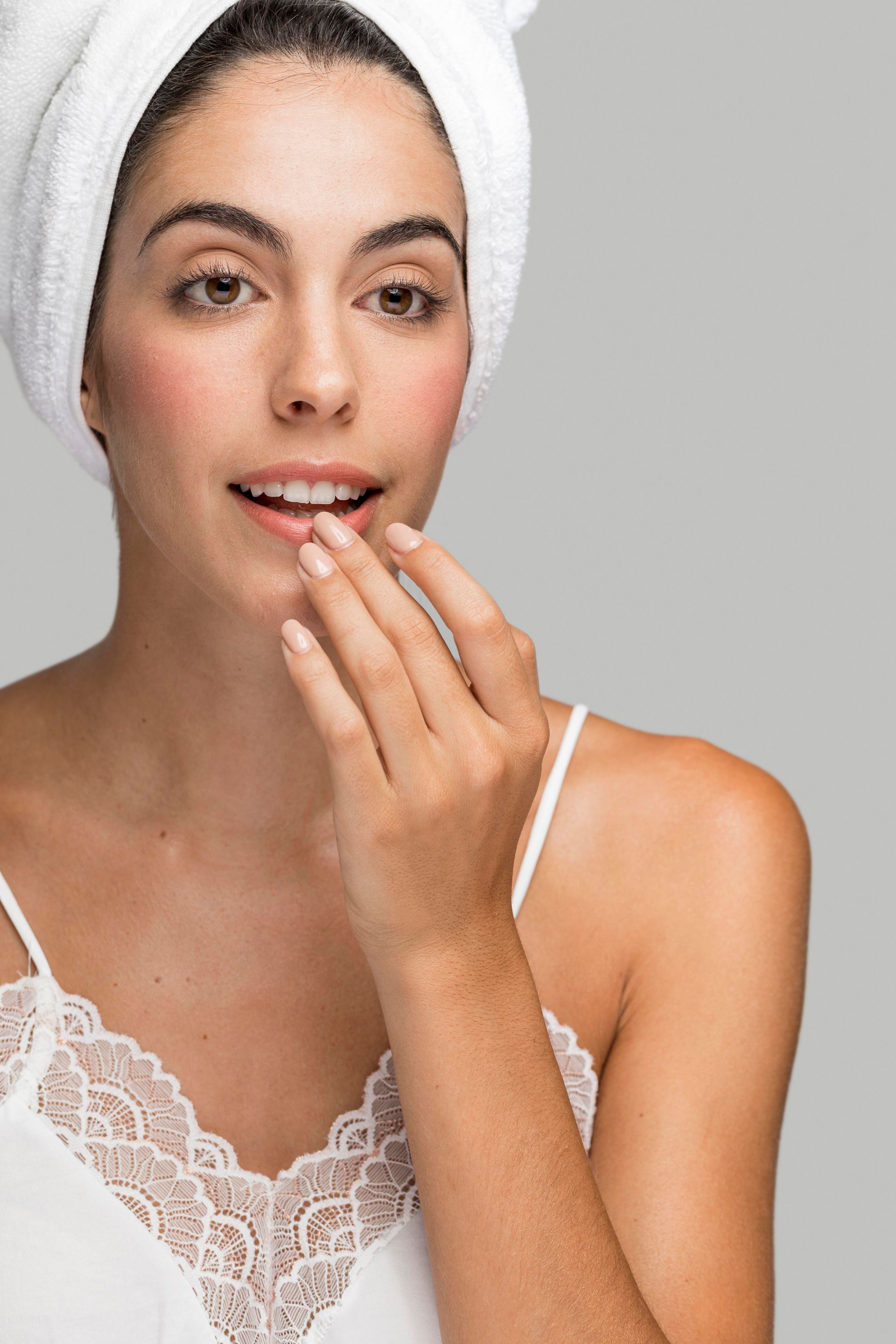 a woman with a towel wrapped around her head is looking at her lips .