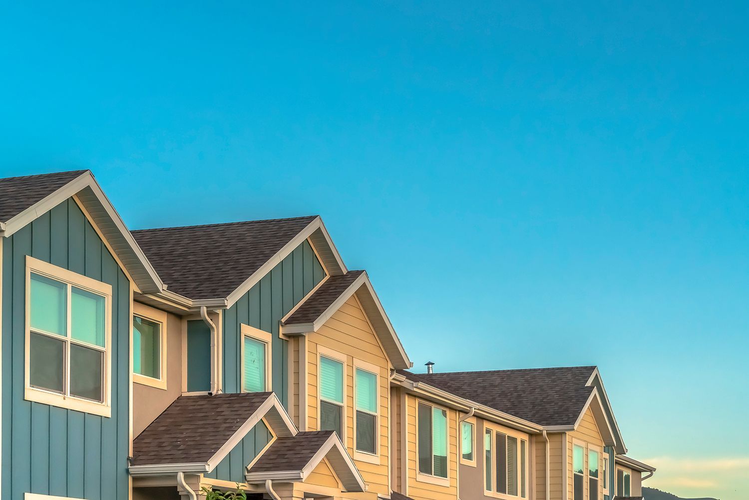 Exterior of upper townhomes with blue sky background.