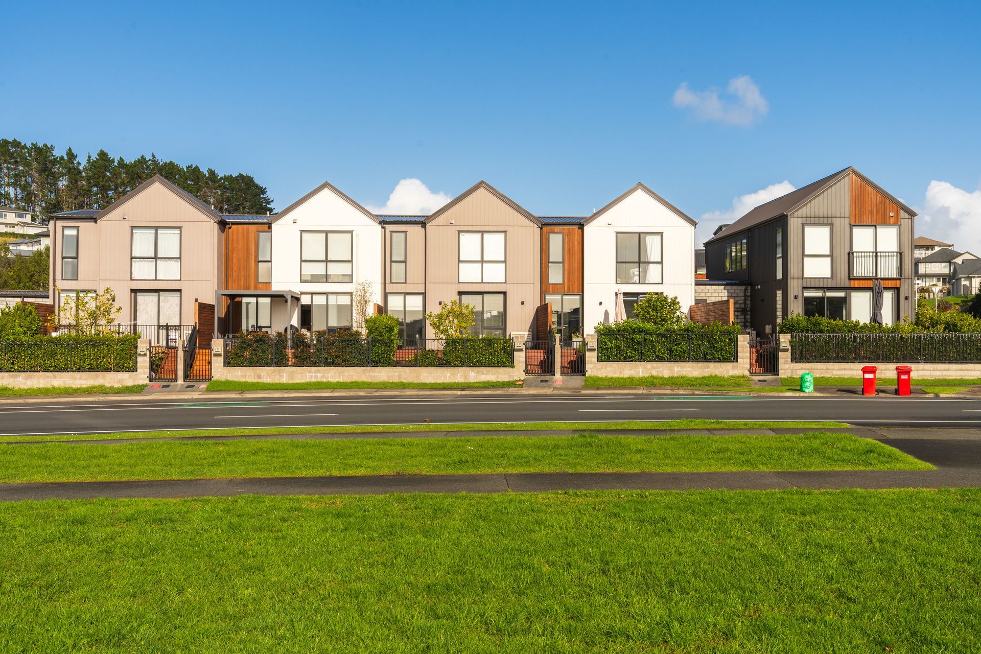 Modern townhouses with green lawns under blue skies on a clean, sunny day.