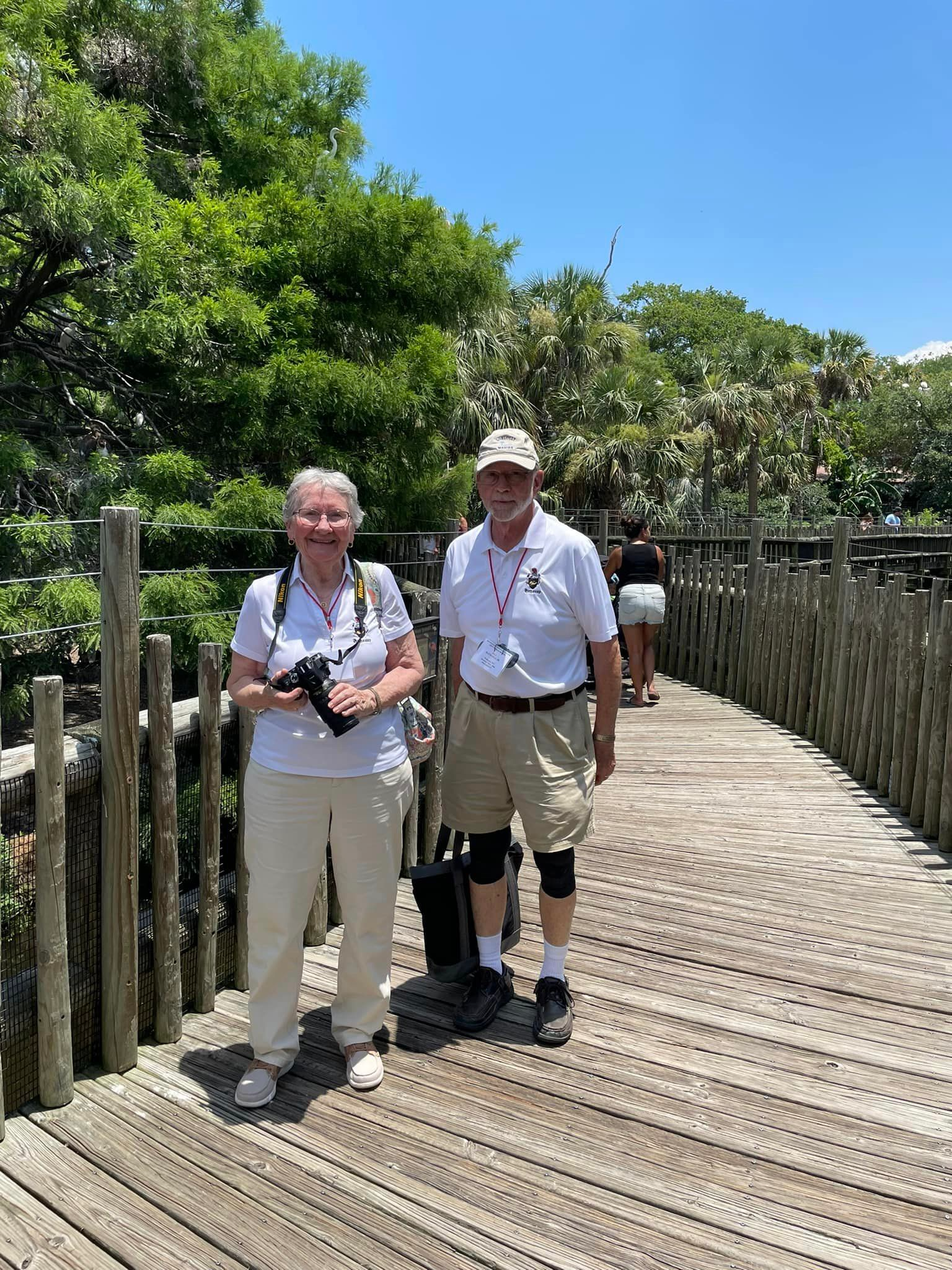 A man and a woman are standing on a wooden bridge.