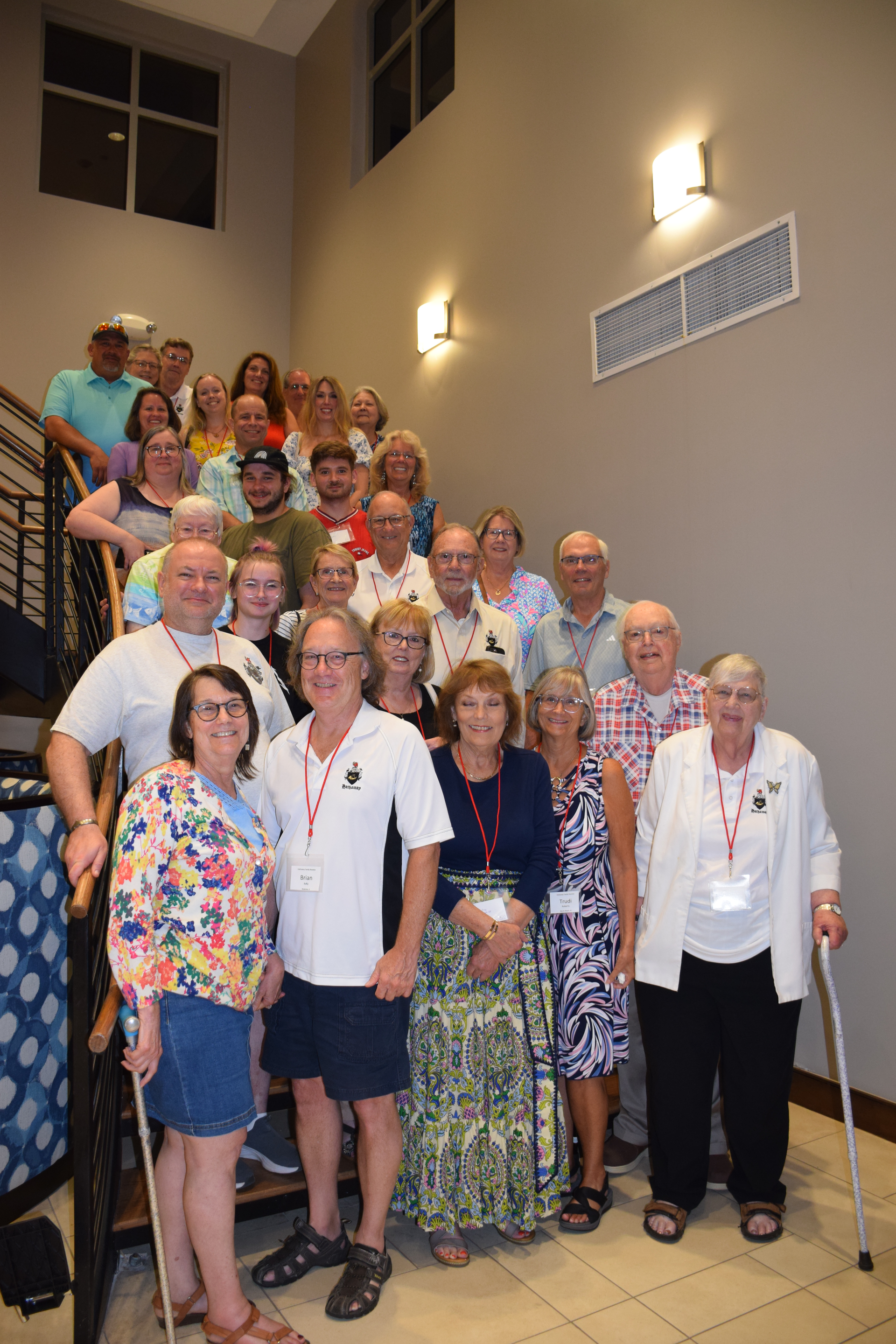 Group of people on stairs; light colored walls; some wearing lanyards.