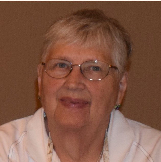 A woman wearing glasses and a white shirt smiles for the camera