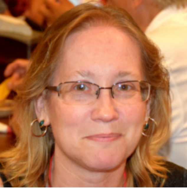 A woman wearing glasses and hoop earrings smiles for the camera