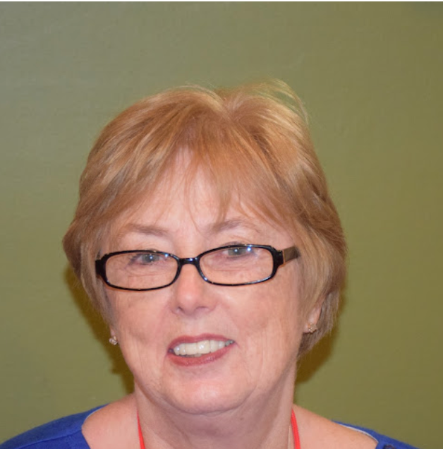 A woman wearing glasses and a blue shirt smiles for the camera
