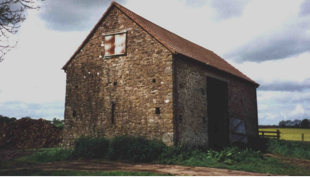 A stone building with a red roof and a white window