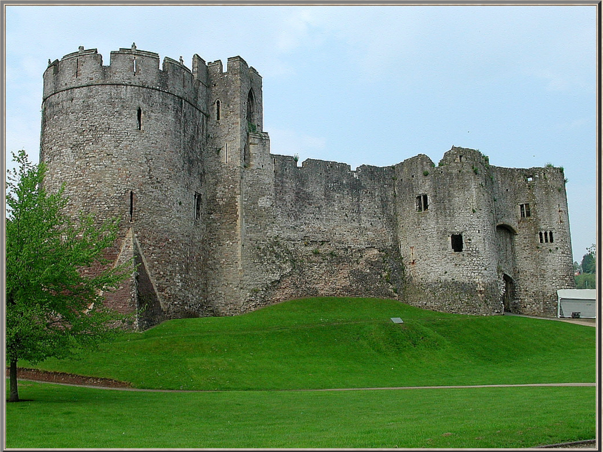 A large stone castle sits on top of a grassy hill