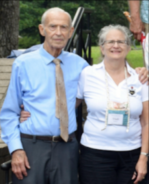 A man in a blue shirt and tie stands next to a woman in a white shirt