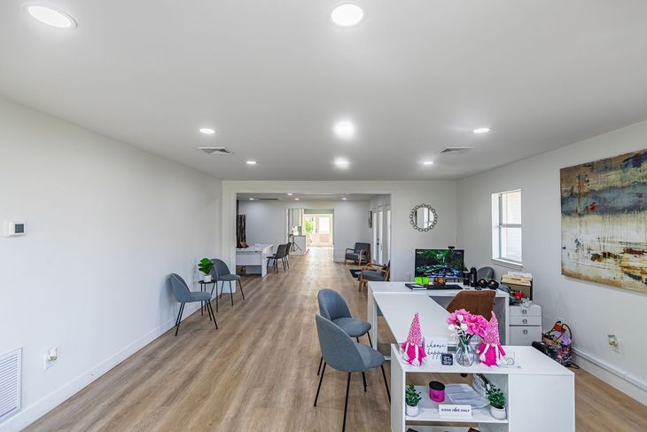 Spacious, well-lit office with light wood floors, reception desk, seating, and art.