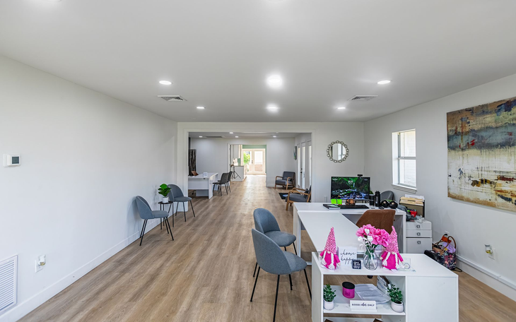 Spacious, well-lit office with light wood floors, reception desk, seating, and art.