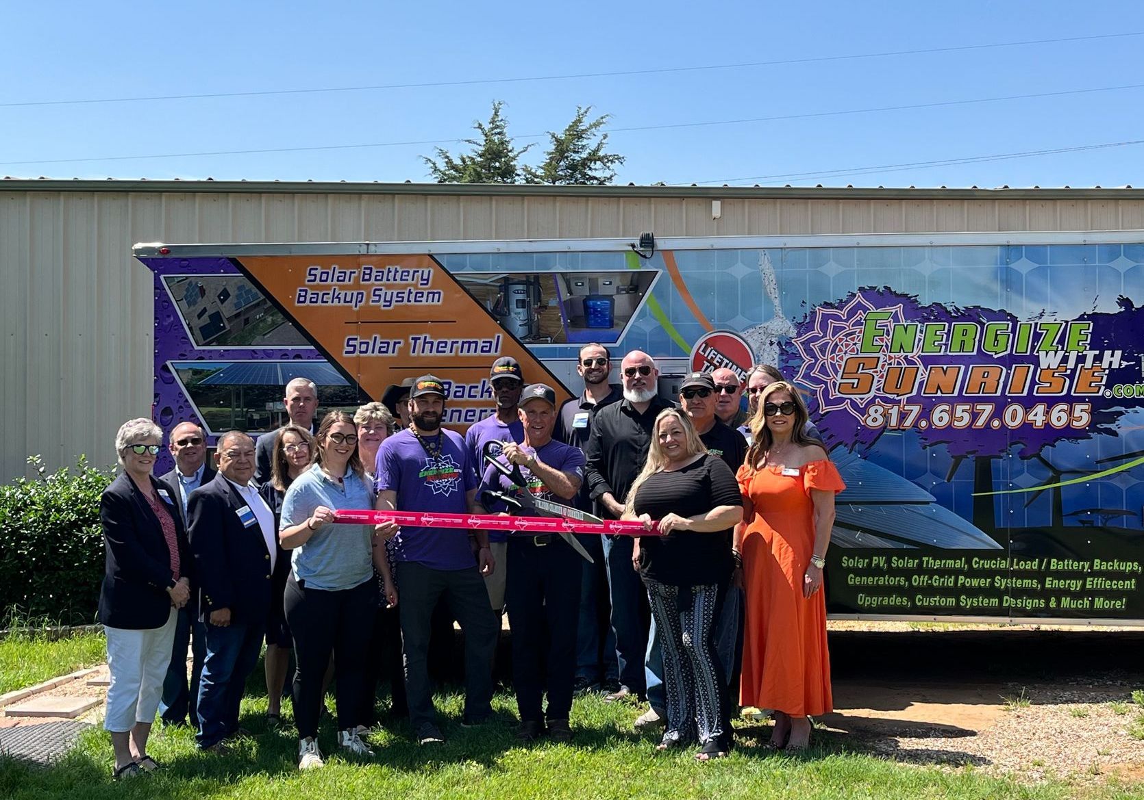 A group of people are cutting a ribbon in front of a truck.