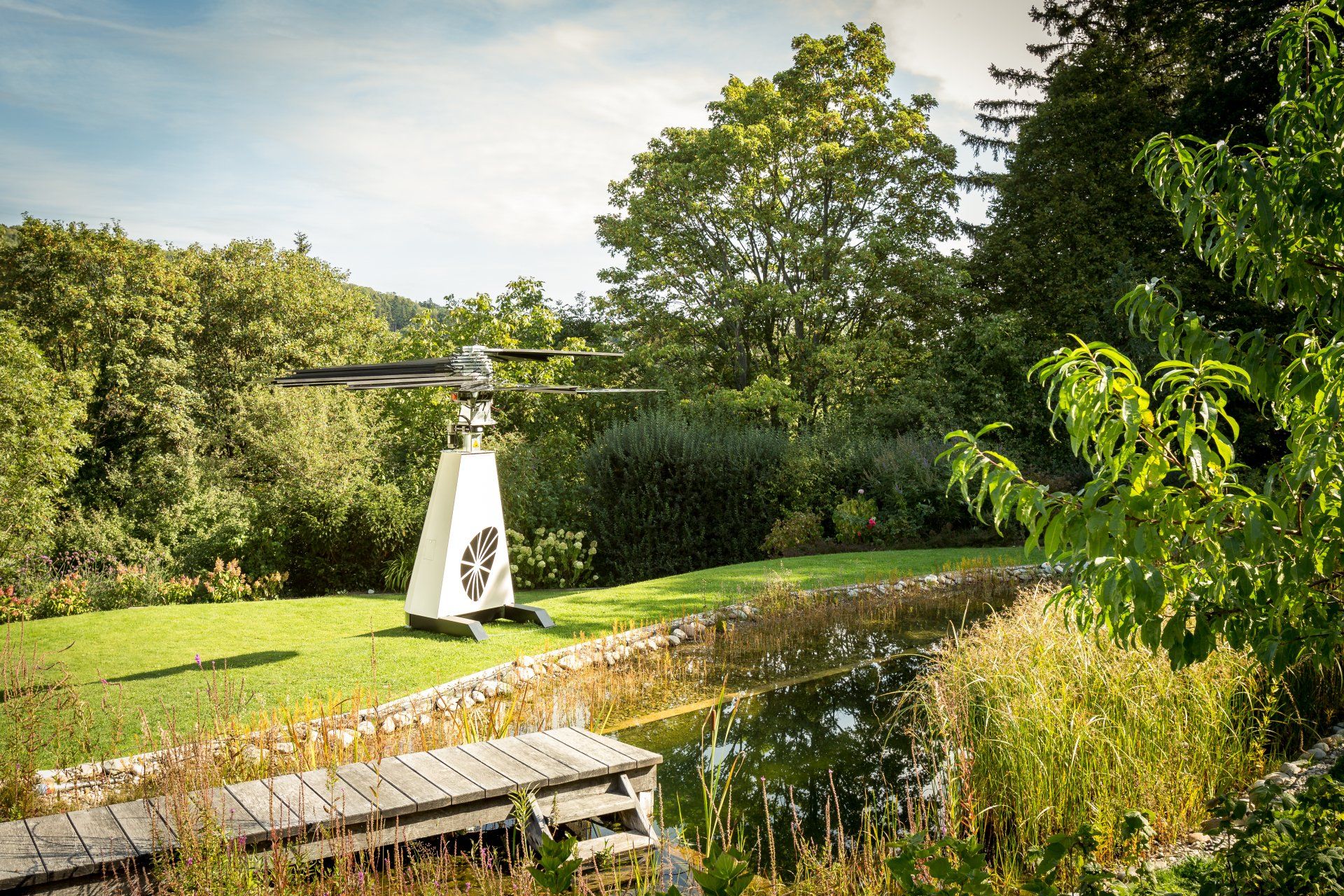 A helicopter is sitting on top of a grass covered field next to a pond.