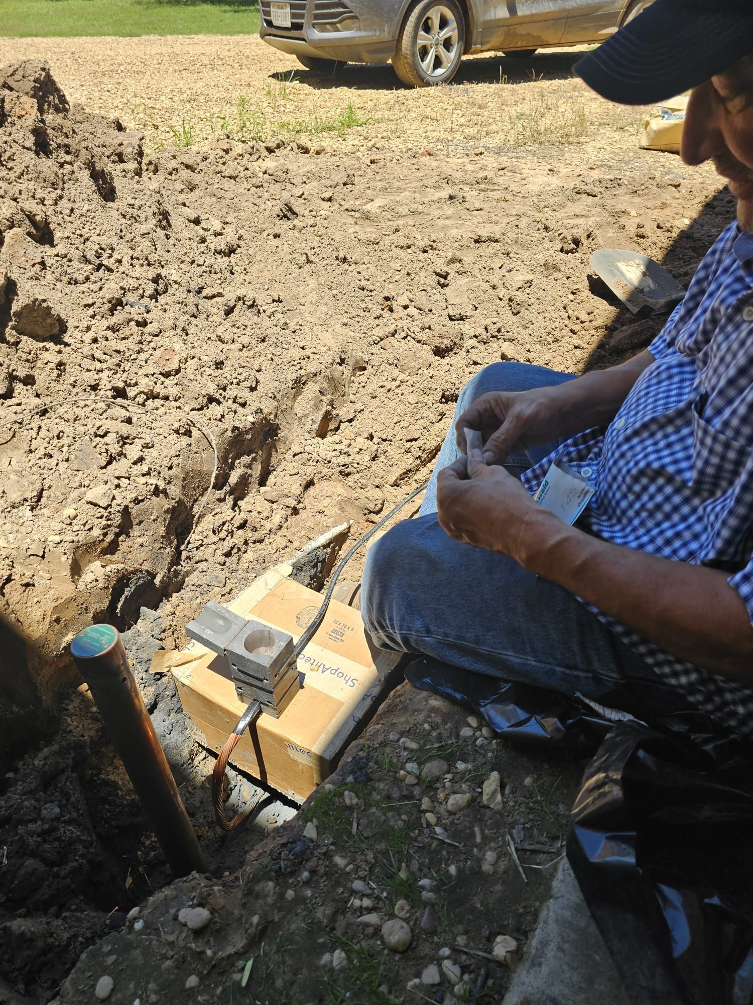 A man is sitting in a field with a box in his hand.