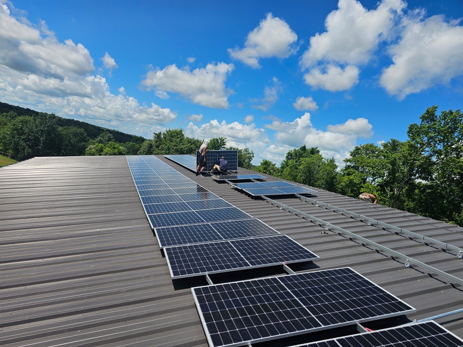 A man is installing solar panels on the roof of a building.