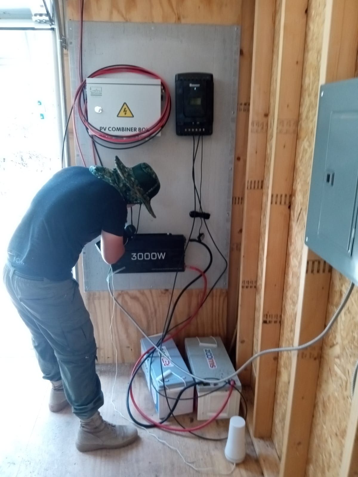 A man in a black shirt is working on an electrical panel.
