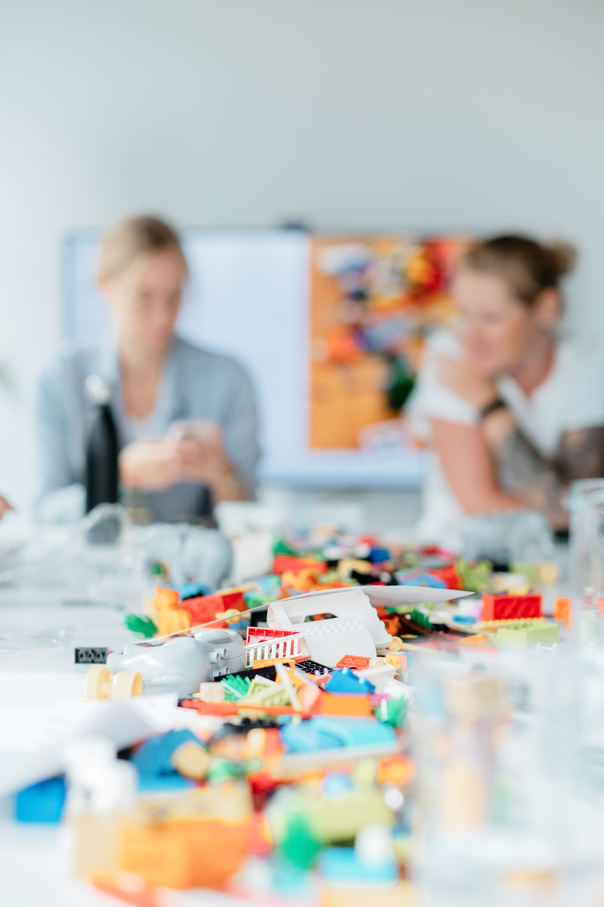 A group of people are sitting at a table with lots of lego blocks on it.