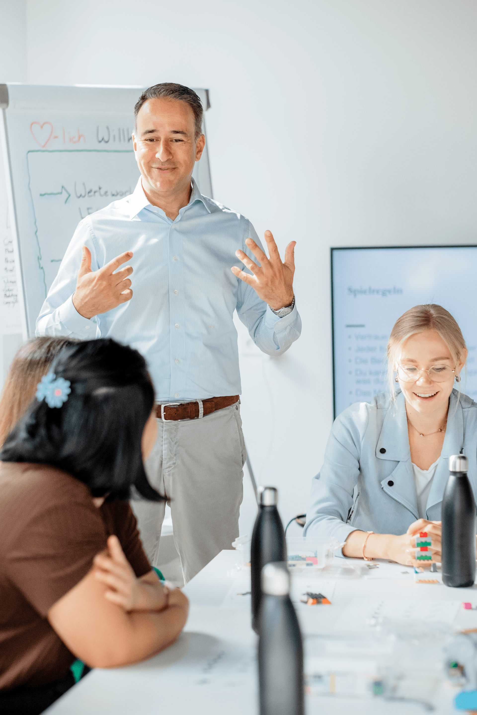 A man is giving a presentation to a group of people sitting at a table.