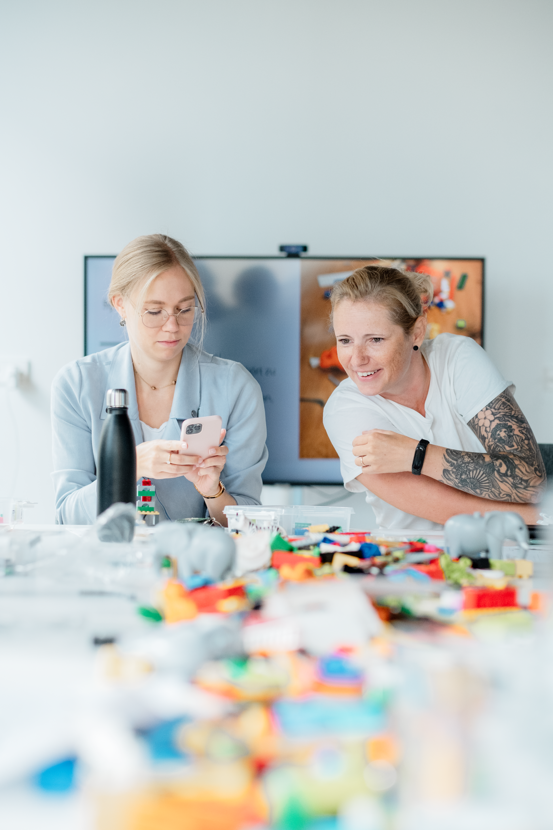 Two women are sitting at a table looking at their phones.