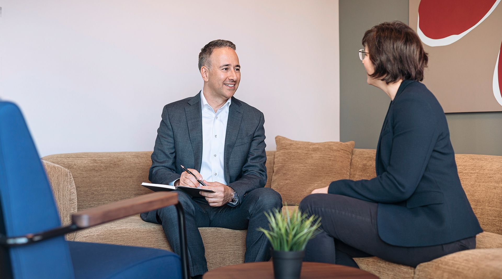 A man and a woman are sitting on a couch having a conversation.