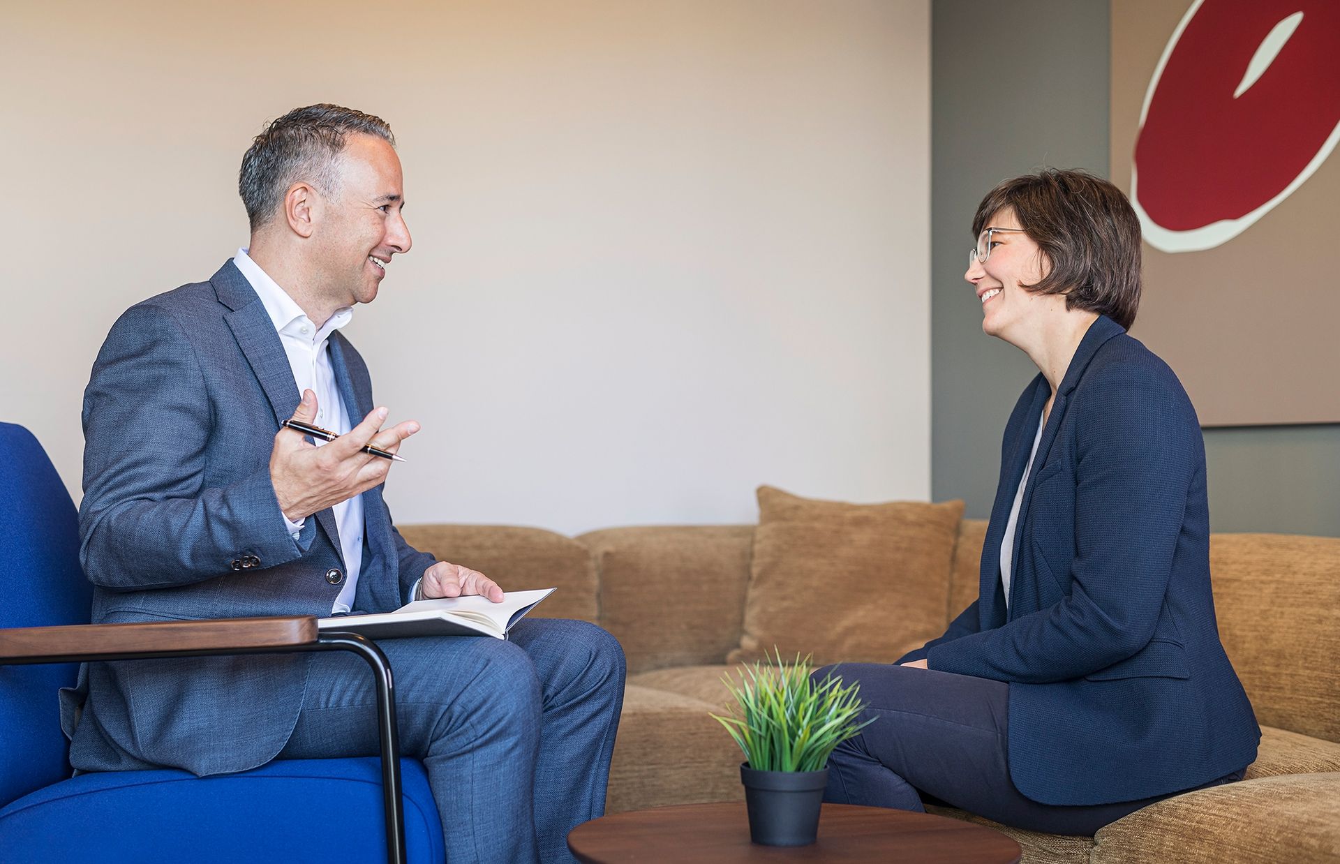 A man and a woman are sitting on a couch having a conversation.