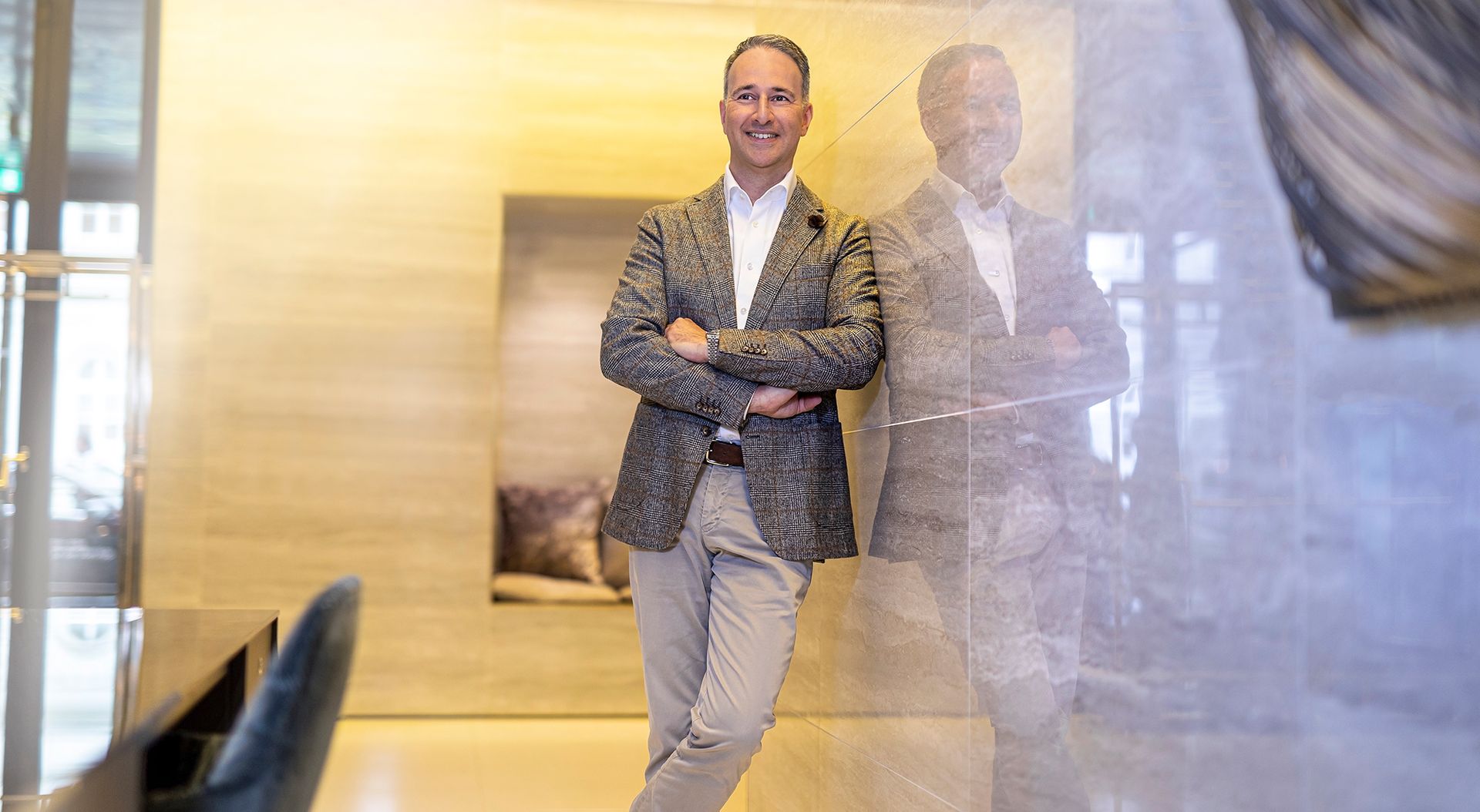 A man in a suit is standing in a room with his arms crossed.