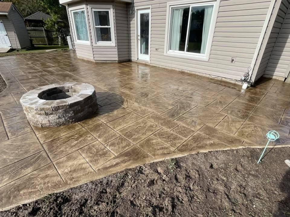 Stamped concrete patio with a fire pit next to a house.