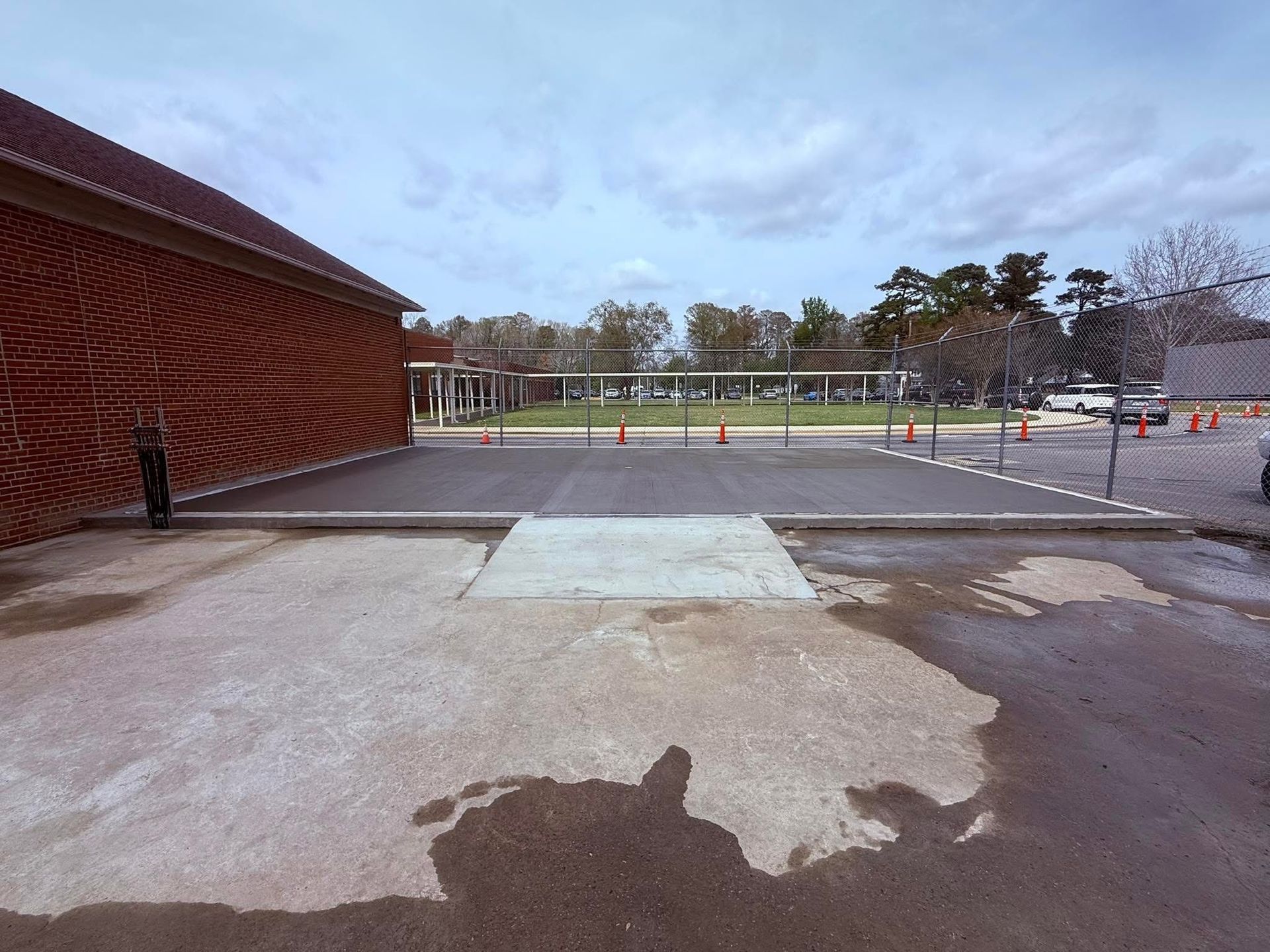 Exterior view of a building with a textured brick wall, concrete surfaces, and metal barriers.