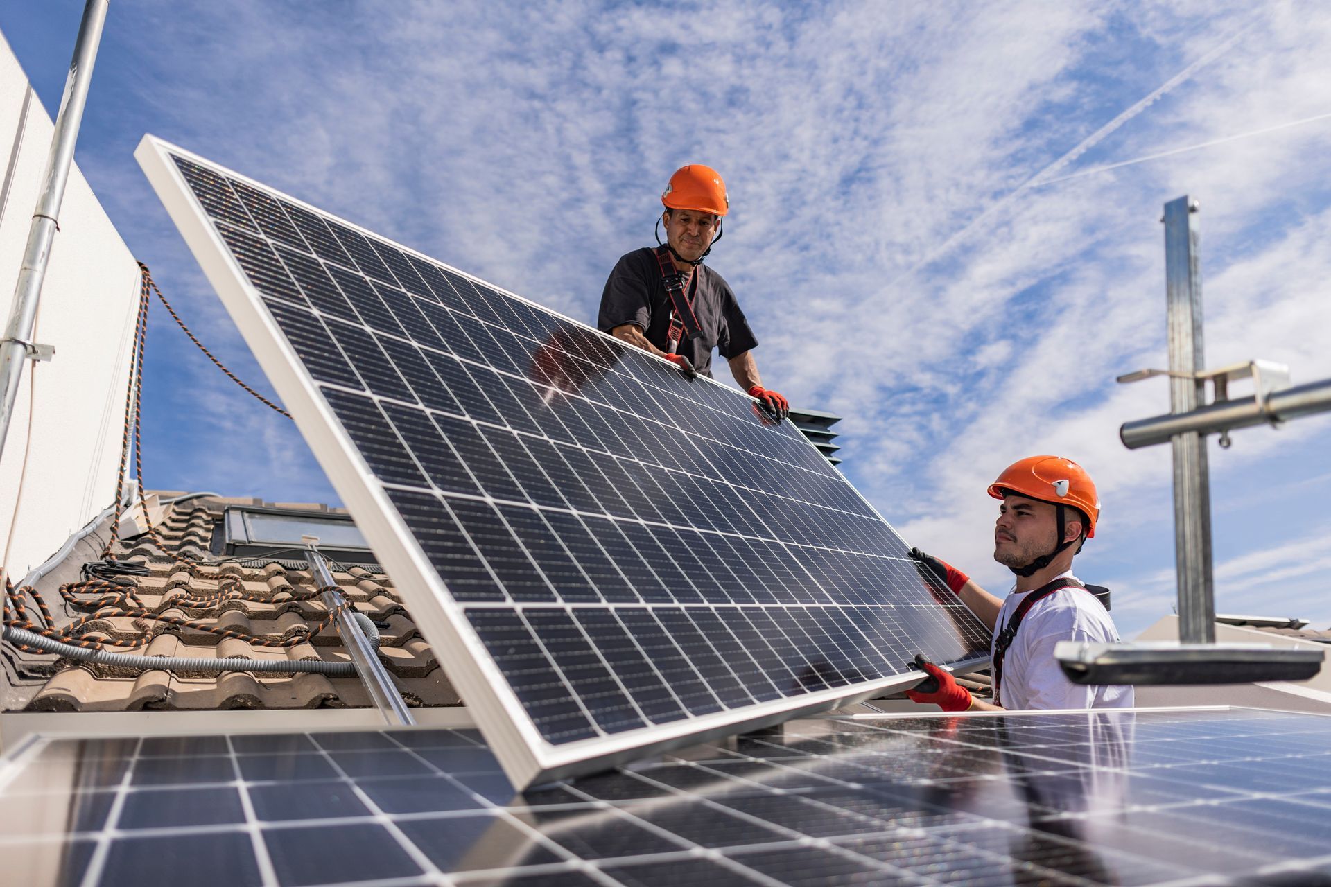 Two engineers wearing hard hats together installing solar panels.