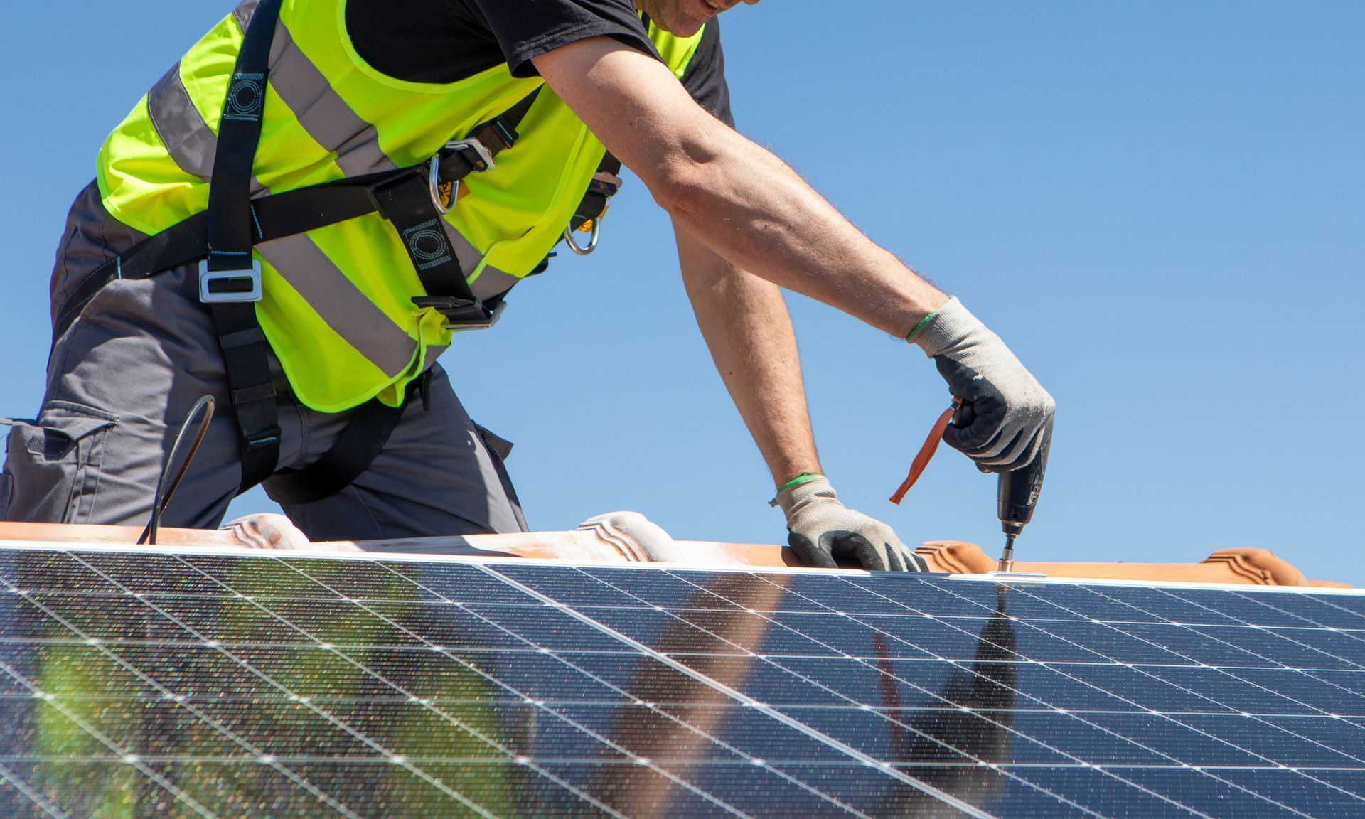 A technician fitting solar panels on a residential roof.