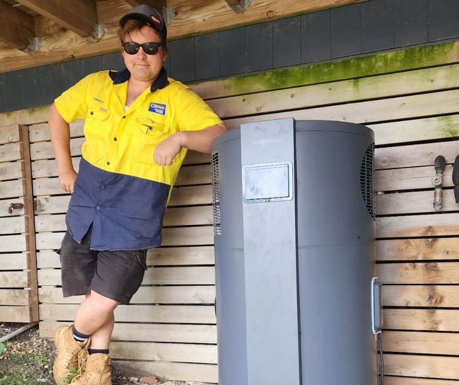 A plumbing professional adjusting the control panel on a hot water system. A plumbing professional adjusting the control panel on a hot water system.