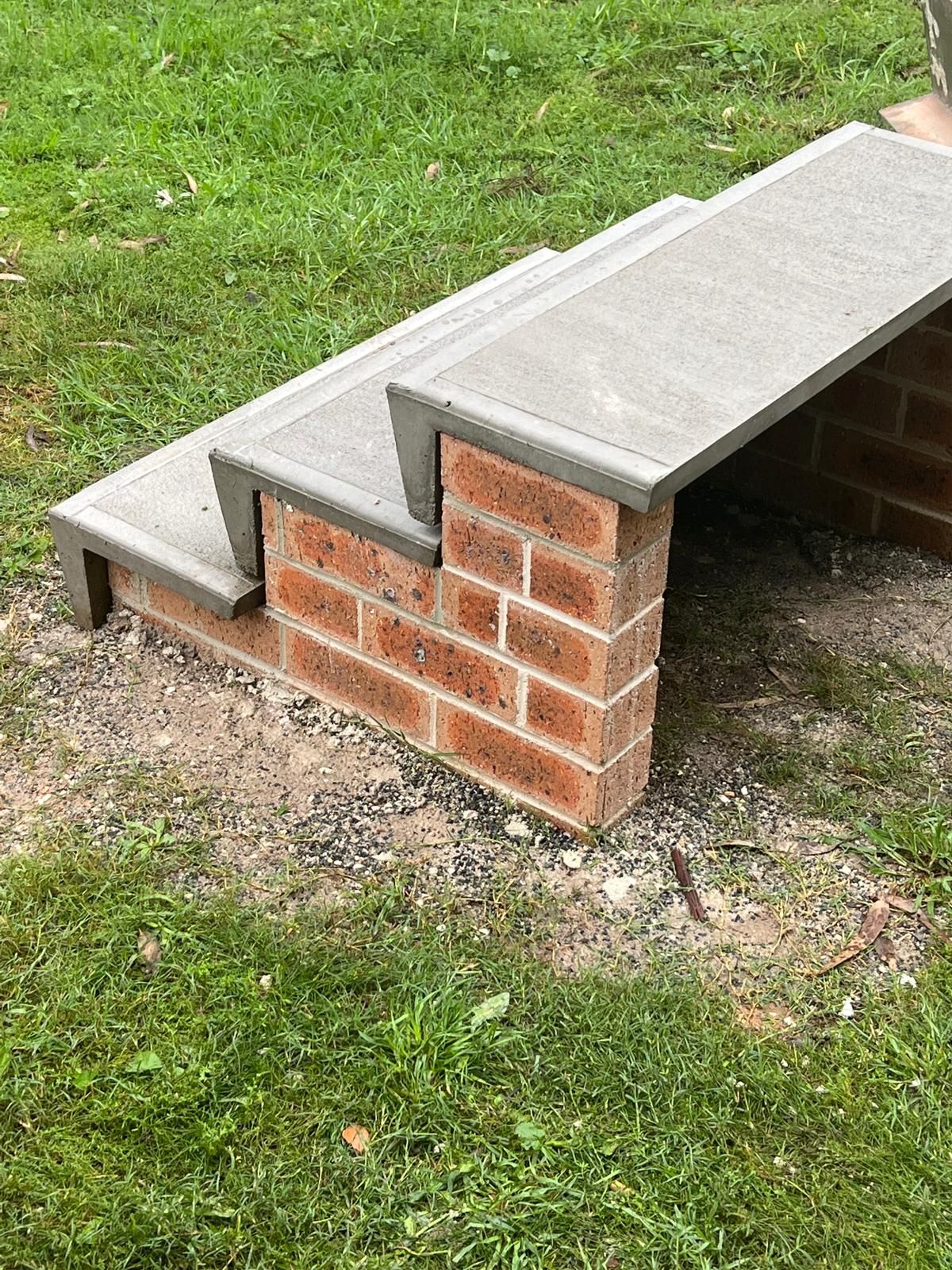 A set of stairs made of bricks and concrete sitting on top of a lush green field.