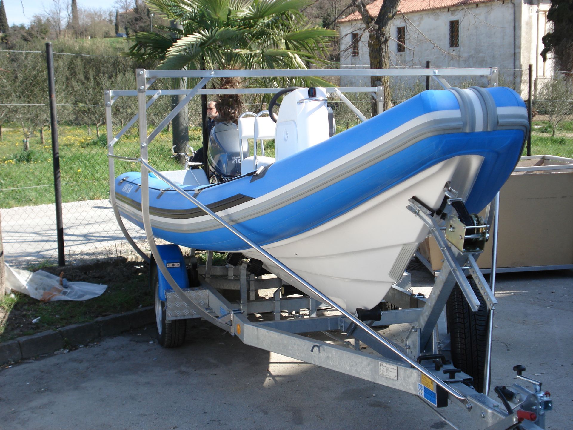 Gommone blu e bianco su rimorchio, all'esterno, con struttura metallica.