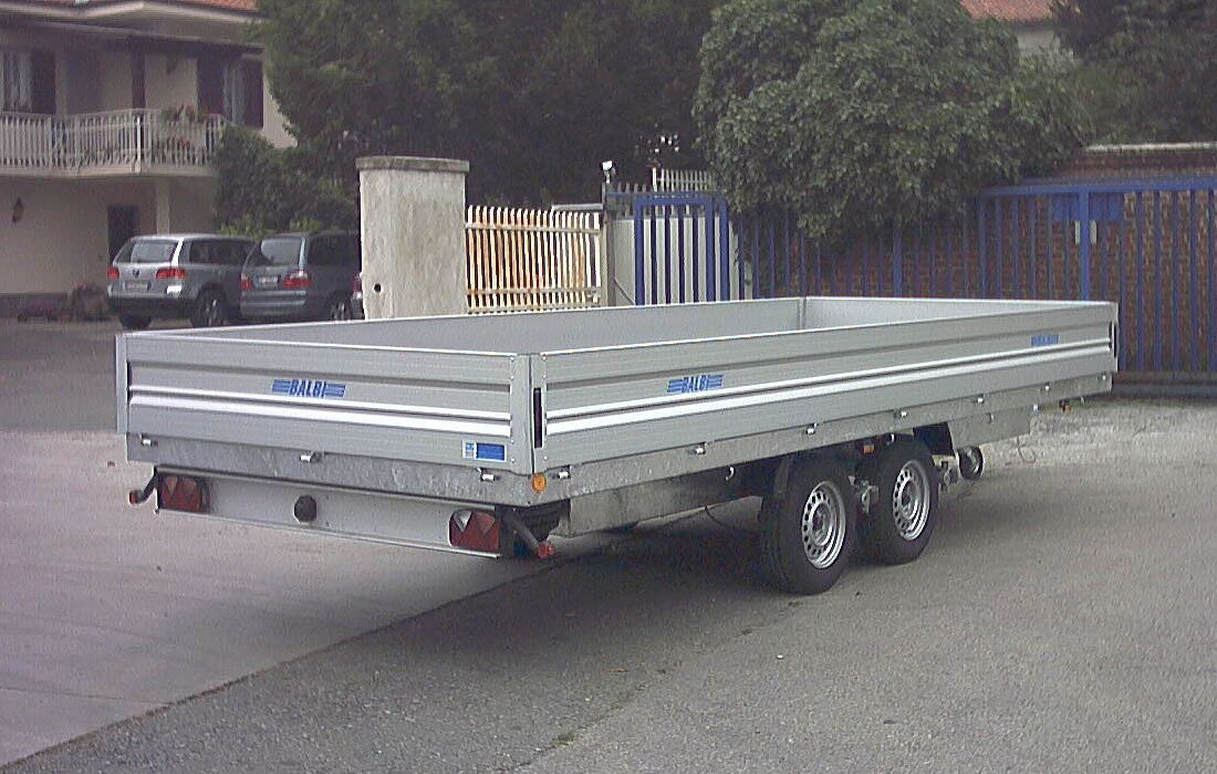 Rimorchio con pianale e doppio asse parcheggiato all'esterno.