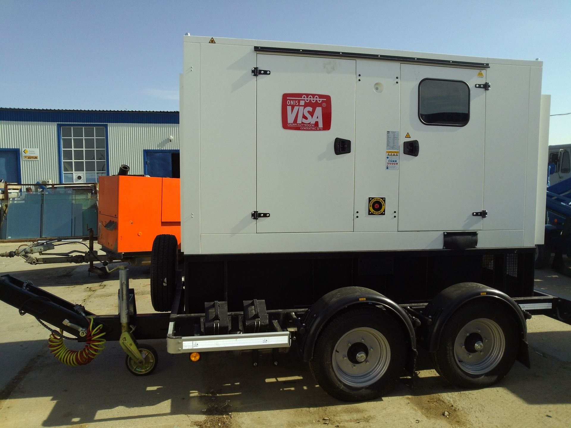 Generatore VISA bianco su un rimorchio, parcheggiato fuori da un edificio in una giornata di sole.