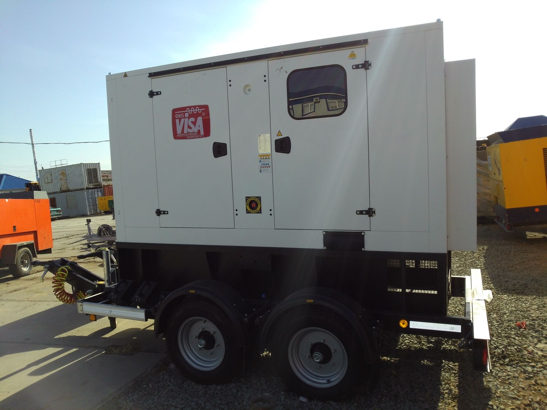 Generatore bianco su un rimorchio a due ruote, in un ambiente esterno. È visibile il logo 