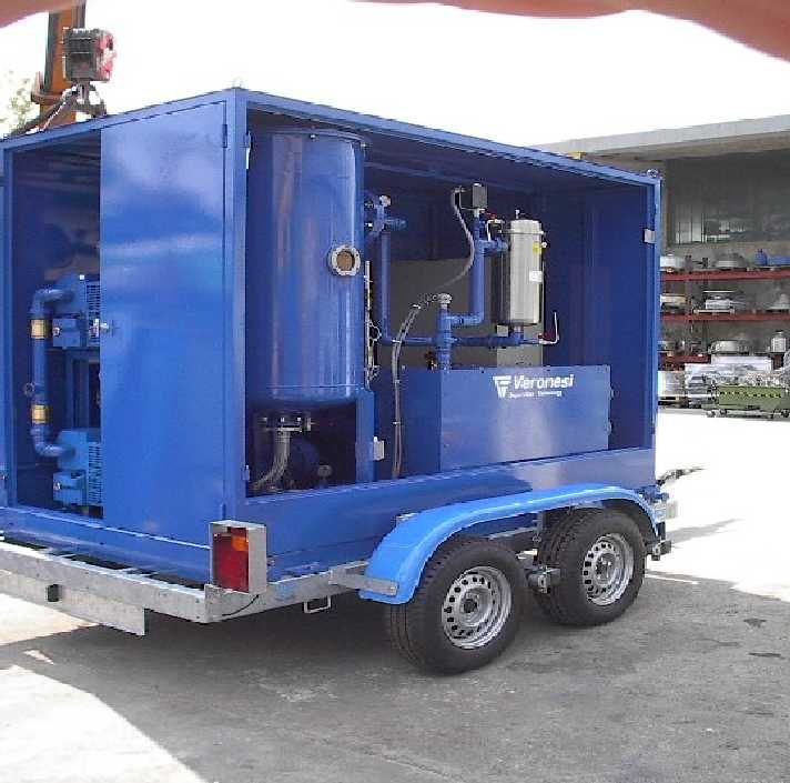 Macchina industriale blu su un rimorchio con due pneumatici, all'aperto.