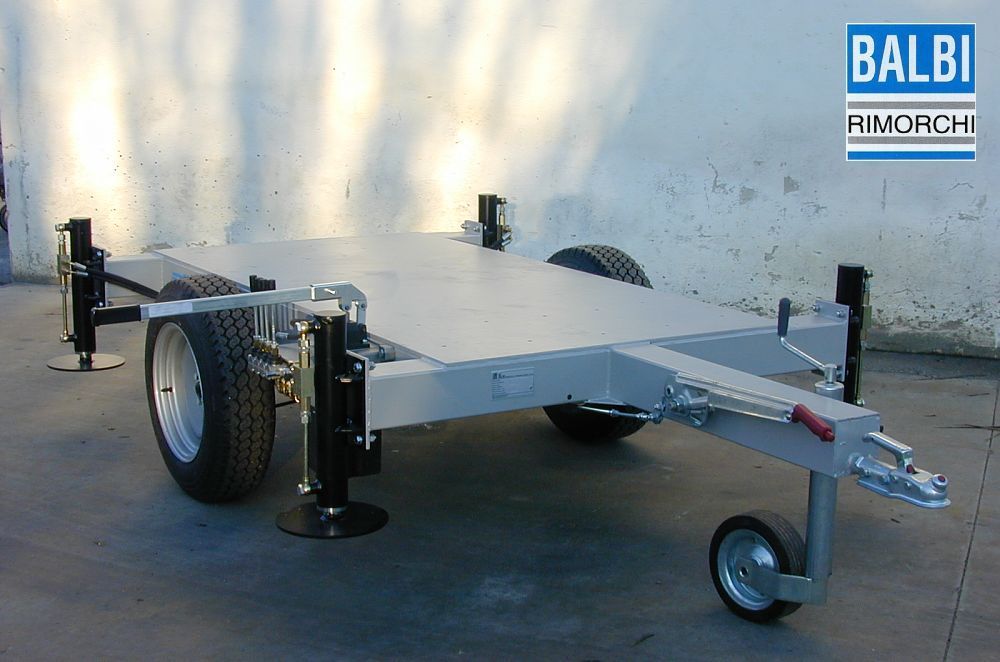 Rimorchio con pianale in alluminio, quattro pneumatici, gancio di traino e martinetti stabilizzatori.