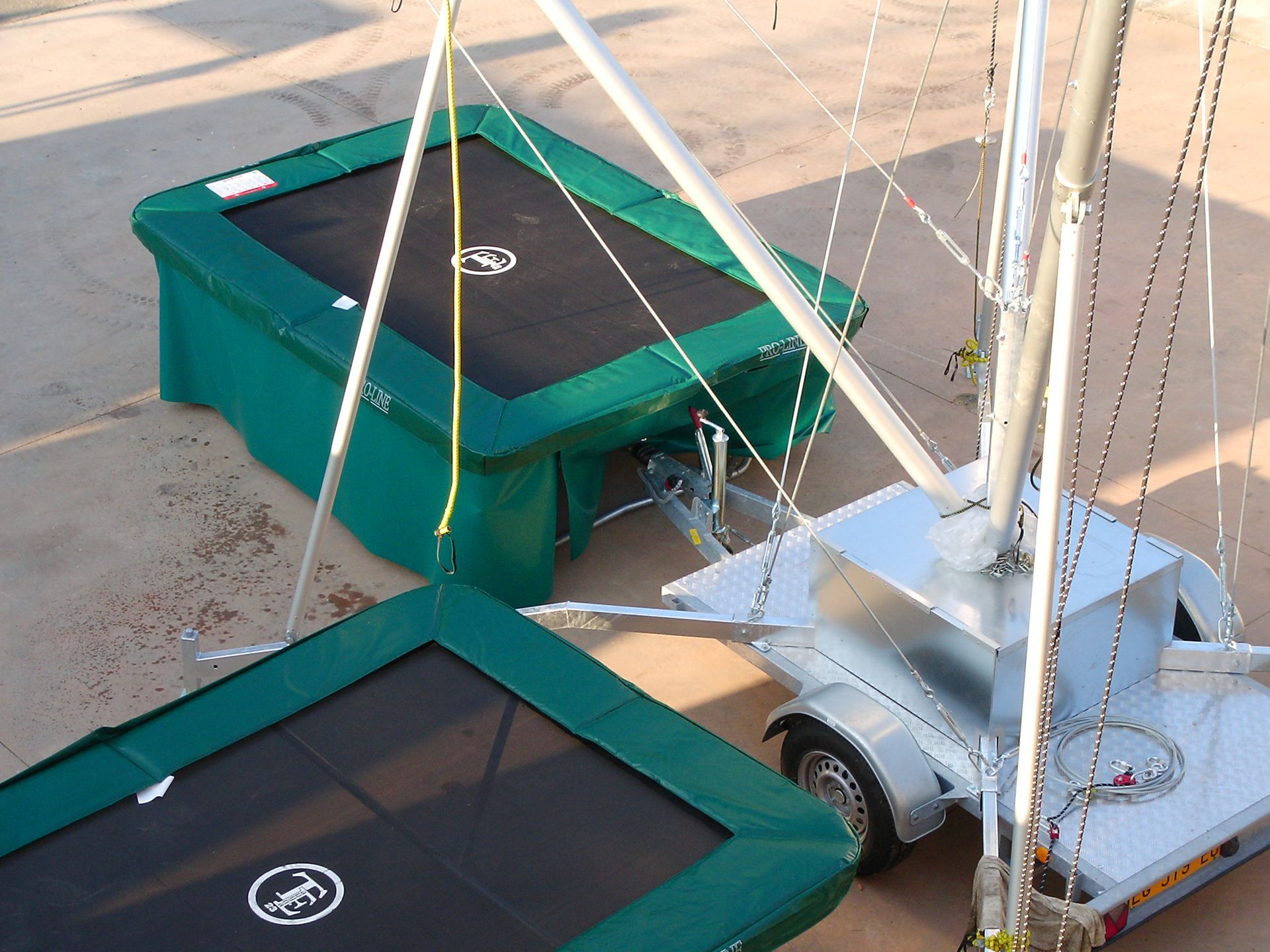 Due trampolini verdi con una torre elastica su un rimorchio, all'aperto.