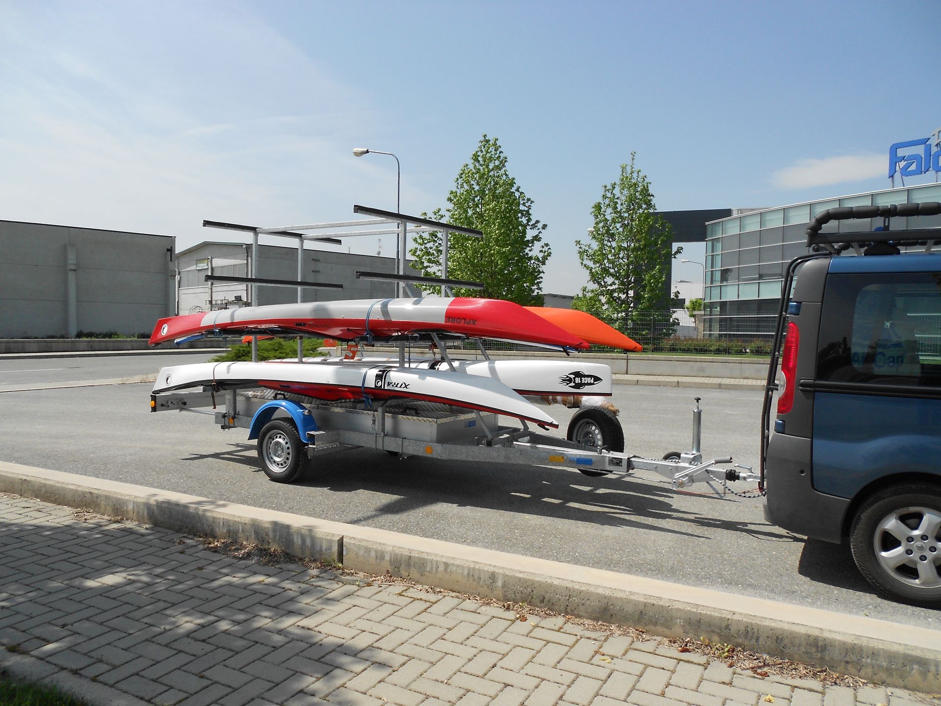 Un'auto che traina un rimorchio carico di due kayak in una giornata di sole.