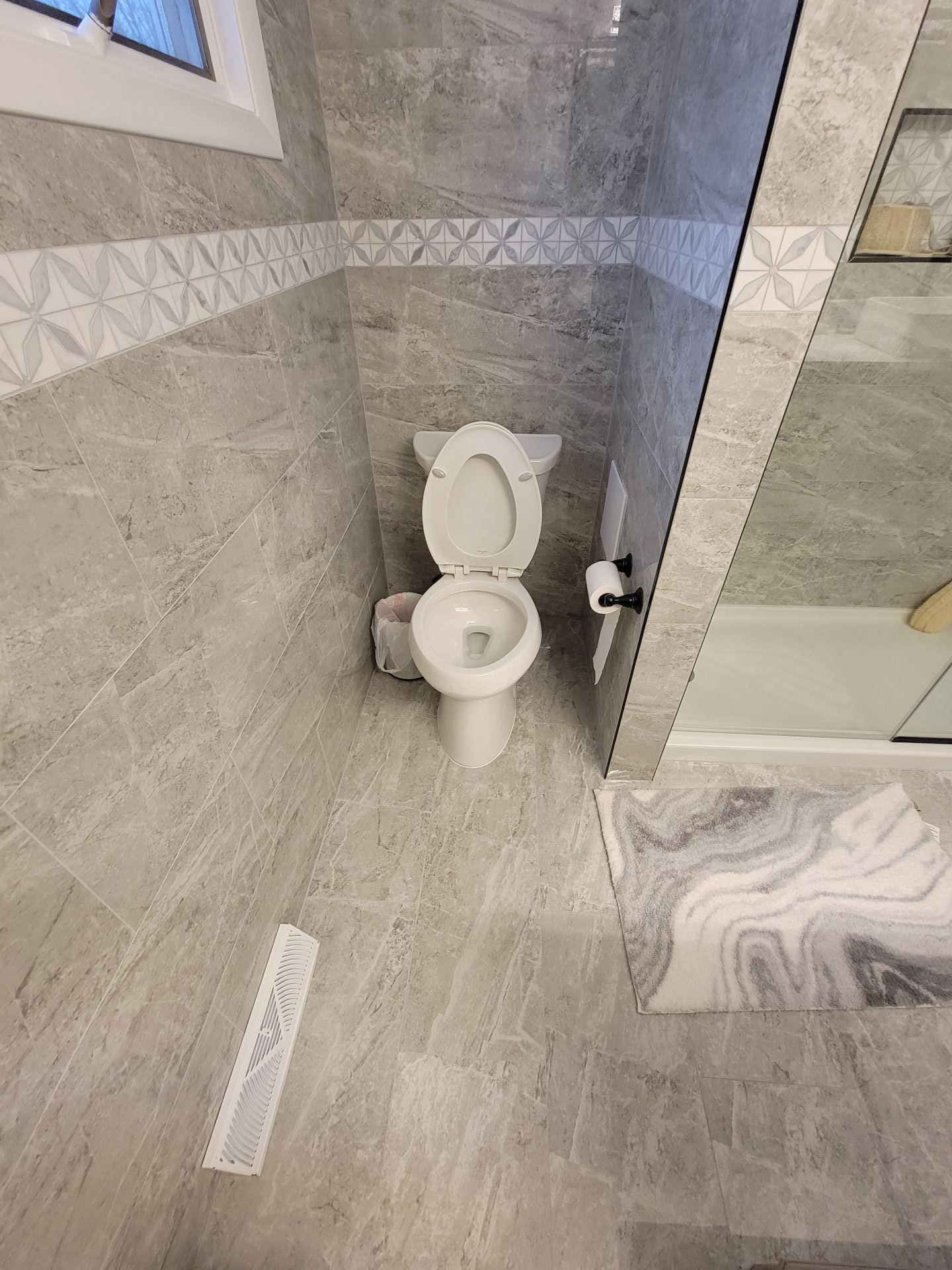 Bathroom with gray tile, toilet, and patterned accents.