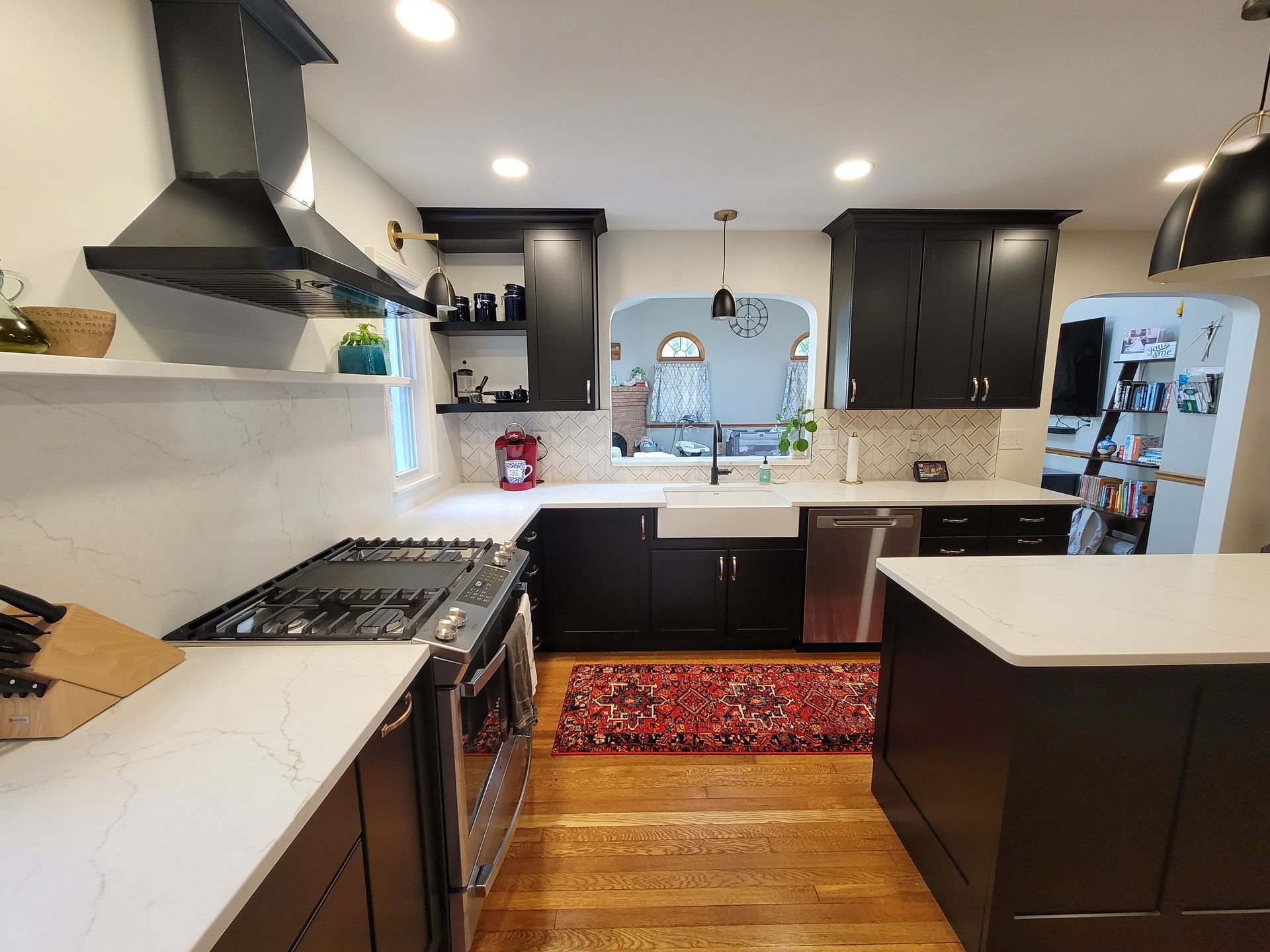 Black and white kitchen with stove, cabinets, and a kitchen island. Wooden floors and patterned rug.
