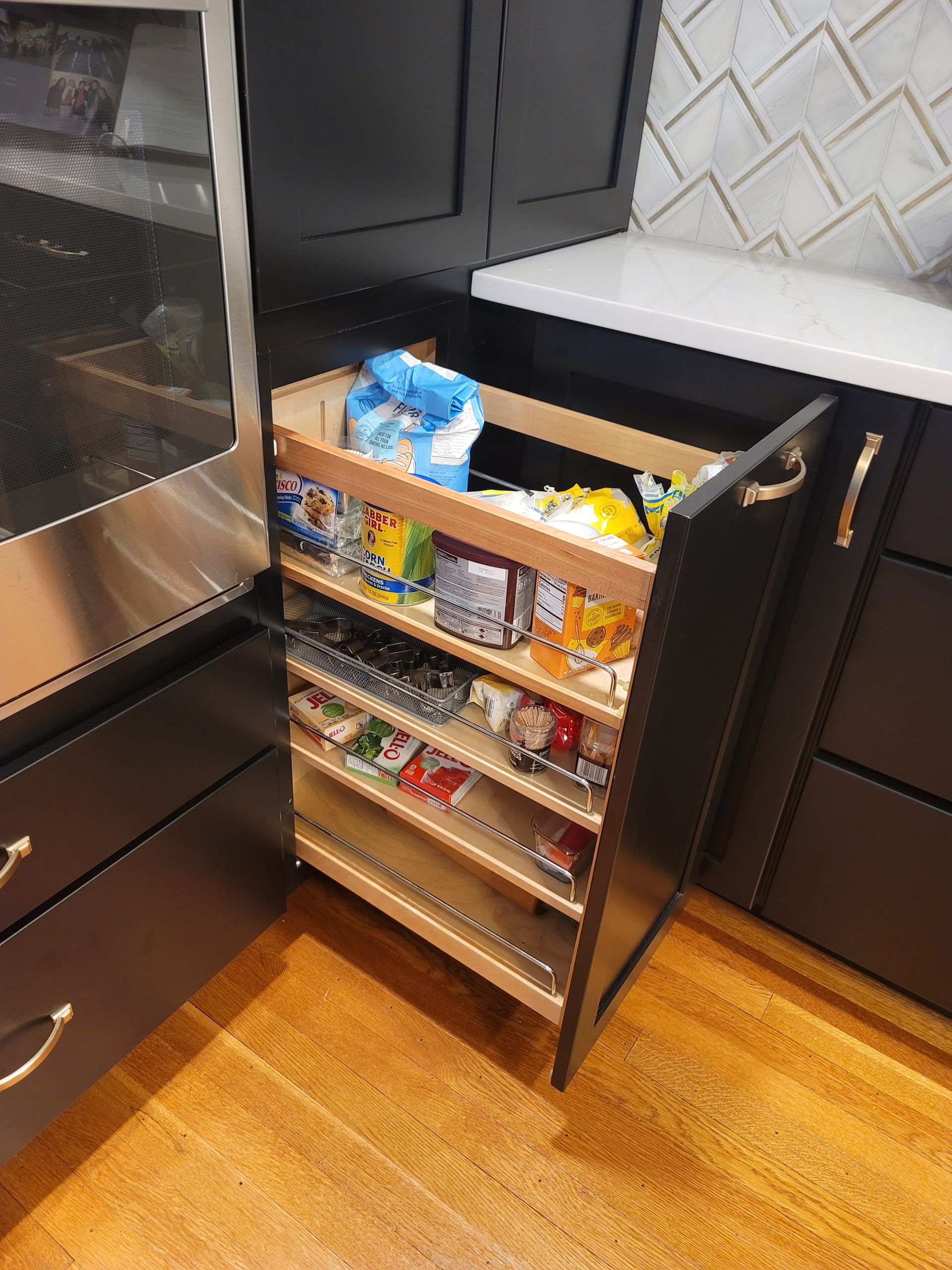 Pull-out pantry cabinet with various snacks and food items in a modern kitchen.