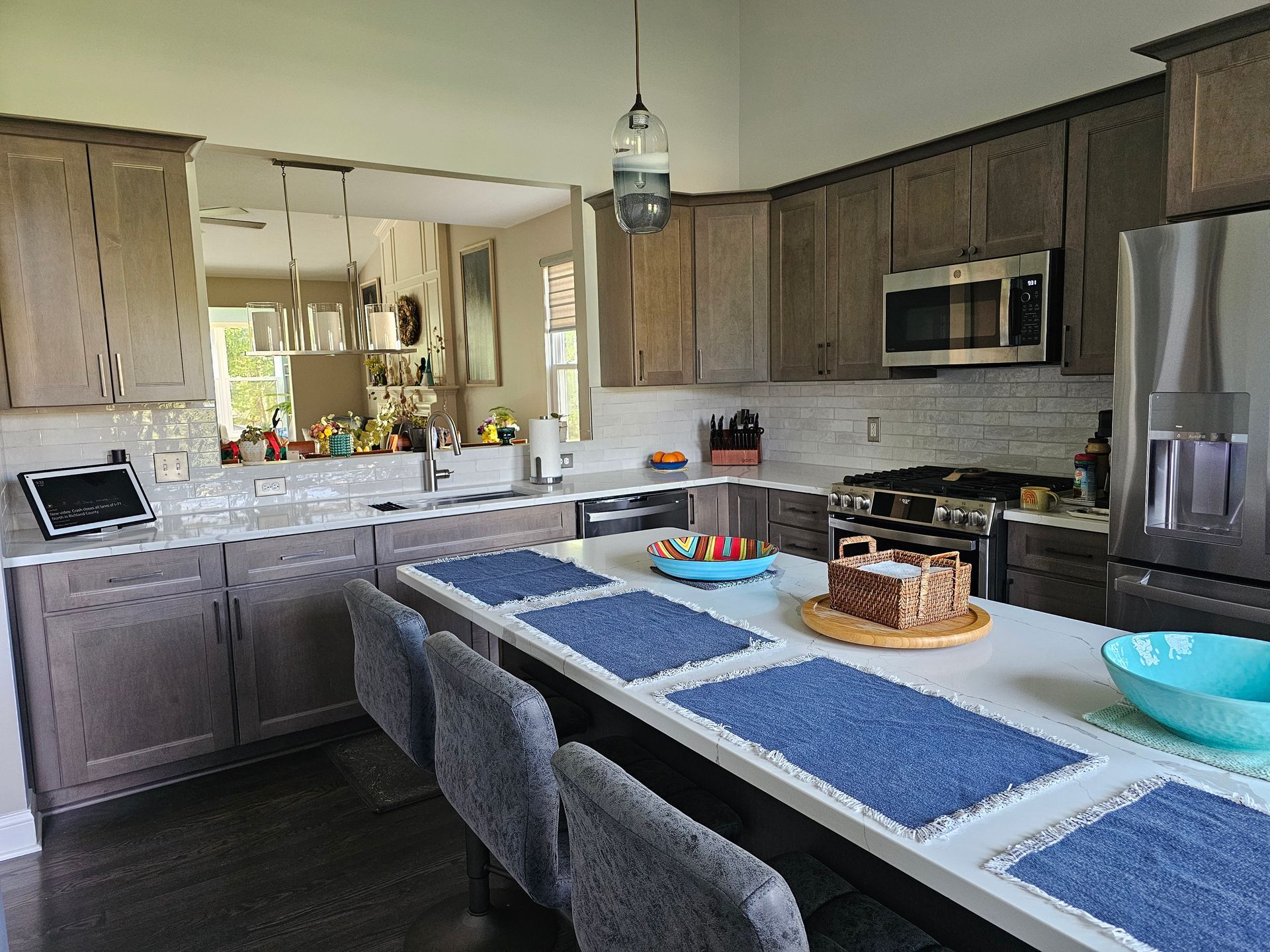 Kitchen with brown cabinets, stainless steel appliances, and island with blue placemats and stools.