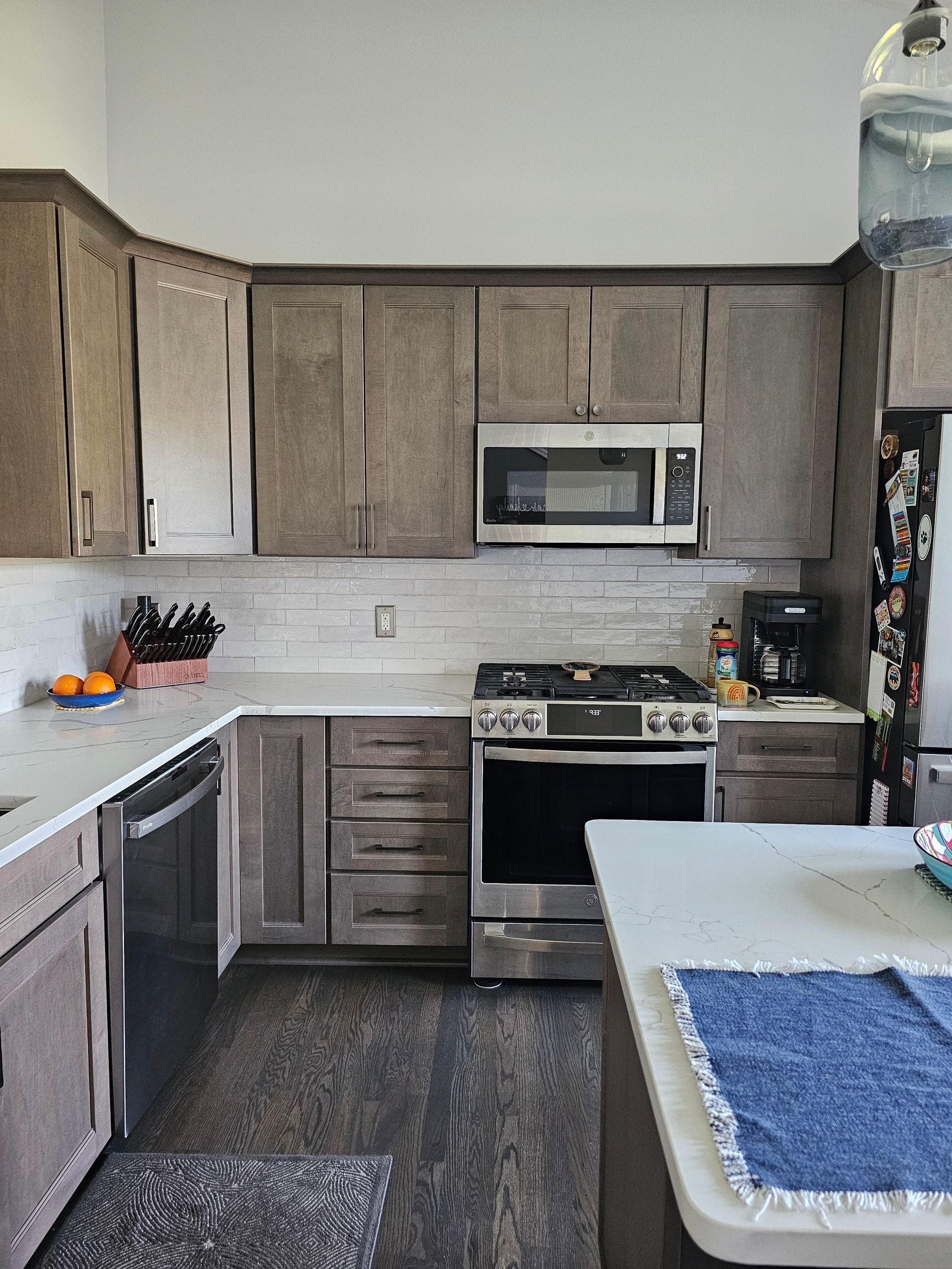 Gray kitchen with stainless steel appliances, light countertops, and dark flooring.