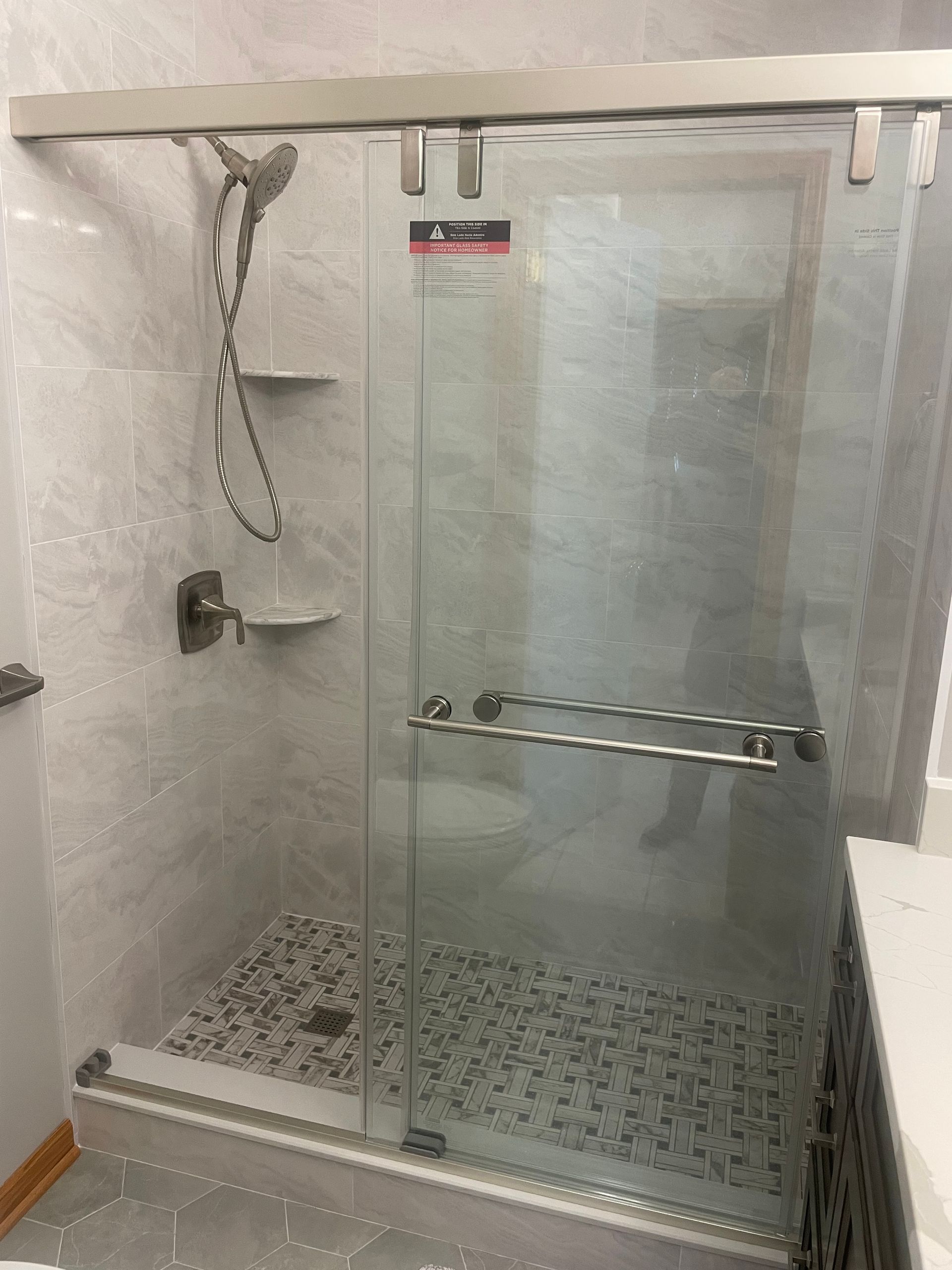 Glass shower enclosure with sliding door and pebble tile floor.