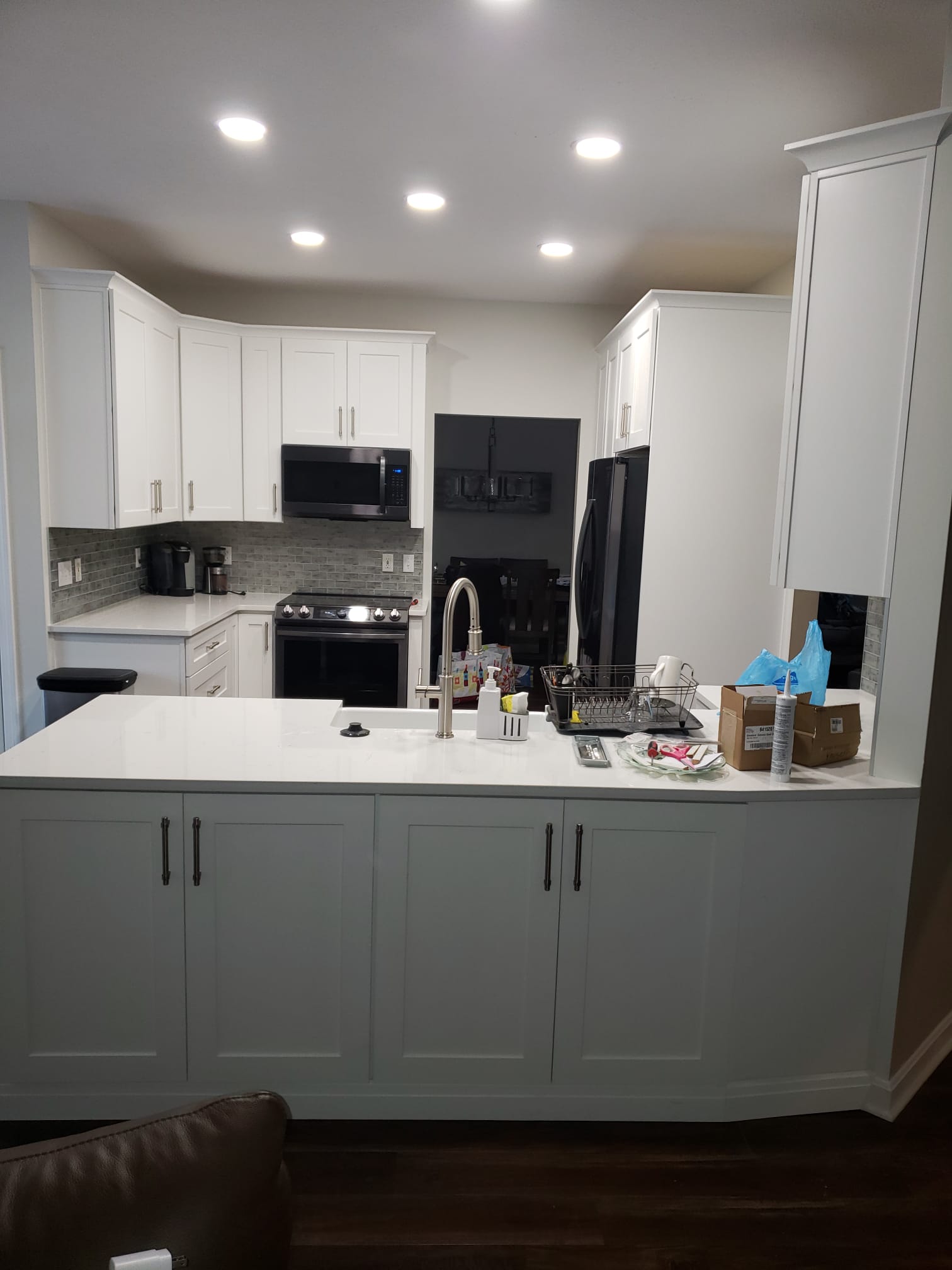 White kitchen with island, cabinets, appliances, and recessed lighting.