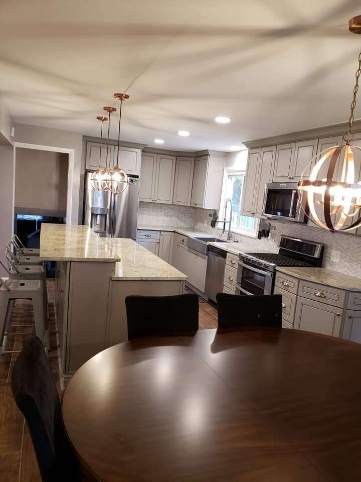 Modern kitchen with light gray cabinets, island, and round dark wooden table.