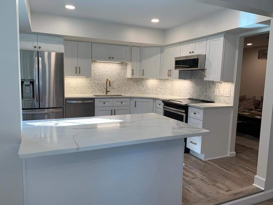 Modern kitchen with white cabinets, stainless steel appliances, and a quartz countertop island.