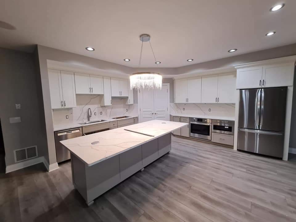 Modern kitchen with white cabinets, gray island, stainless steel appliances, and gray flooring.